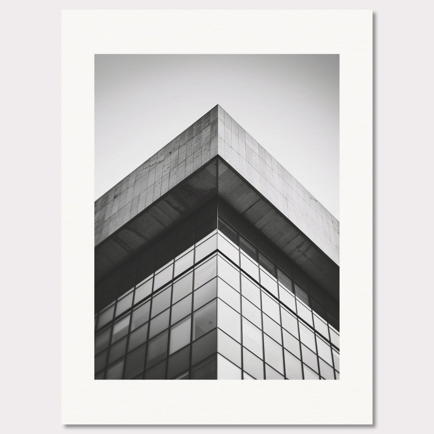 This striking black and white photograph captures the sharp, geometric lines of a modern architectural structure. The image focuses on the corner of a building, emphasizing its sleek glass windows and concrete elements.