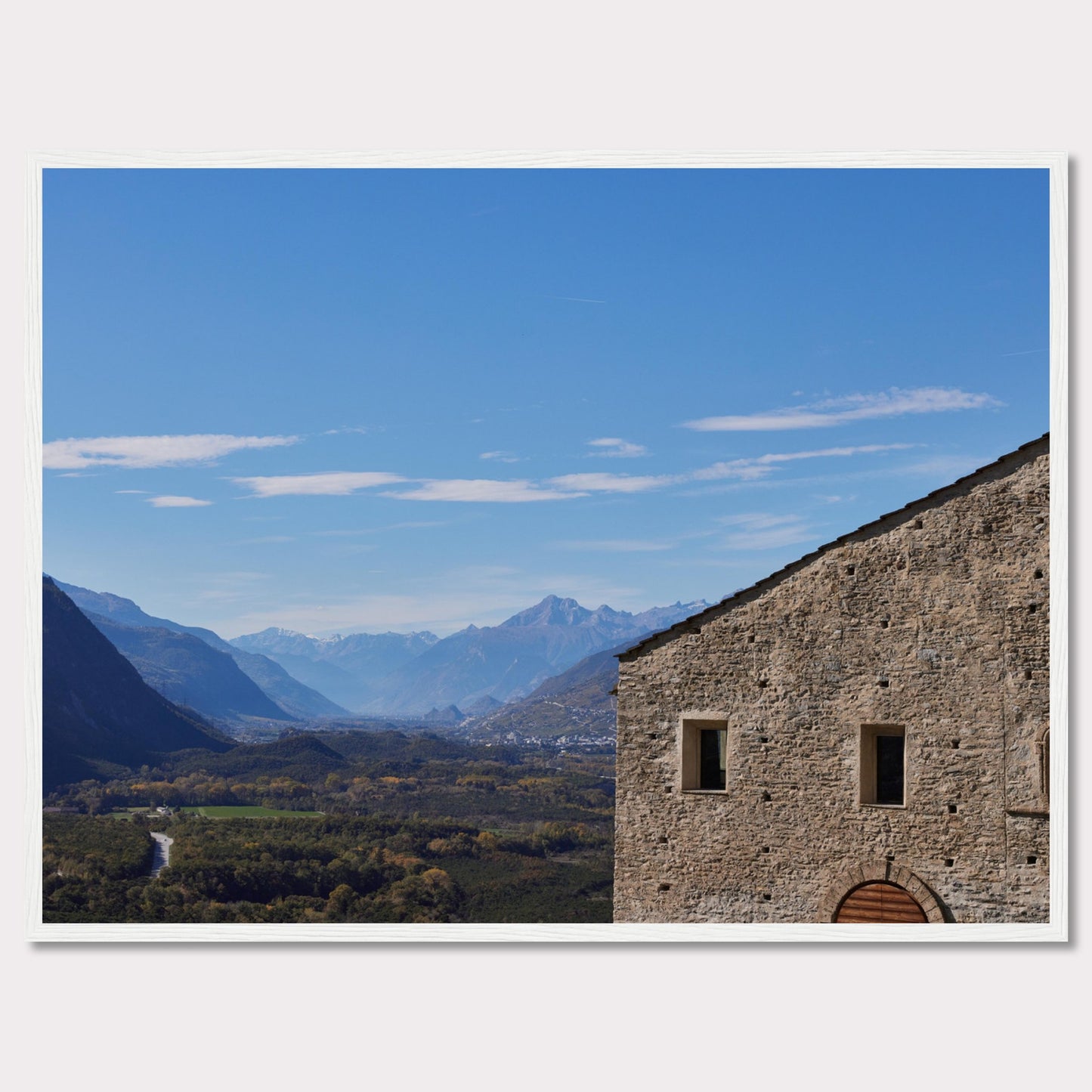 This stunning photograph captures a serene landscape with a historic stone building in the foreground and majestic mountains in the background.