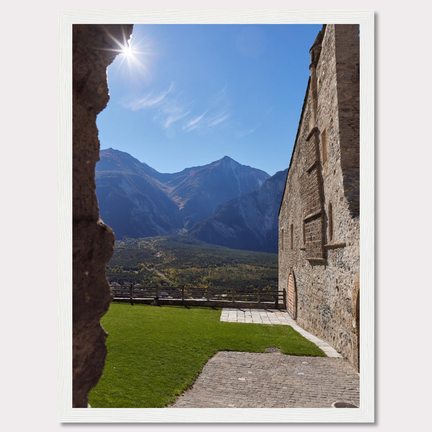 This captivating image showcases a stunning view of a mountainous landscape framed by the rustic stone walls of an ancient structure. The bright sun shines above, casting a warm glow over the scene.