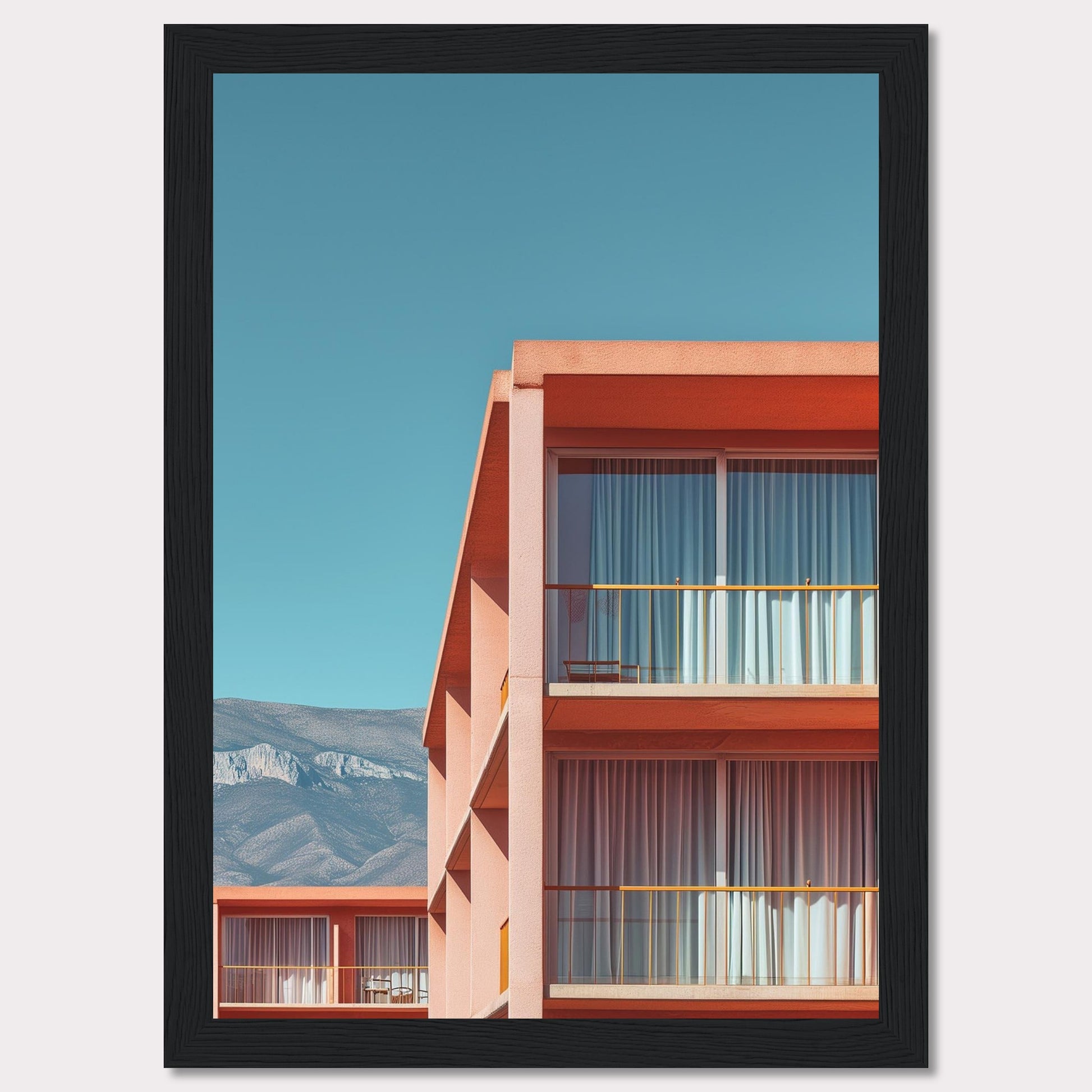 This captivating image showcases a modern building with a vibrant orange facade under a clear blue sky. The structure features large glass windows with white curtains, and balconies equipped with minimalistic furniture. In the background, majestic mountains add a serene touch to the scene.